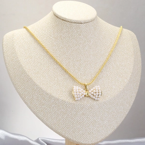 Elegante goldene Halskette mit perlenbesetztem Schleifenanhänger an einer feinen Kette