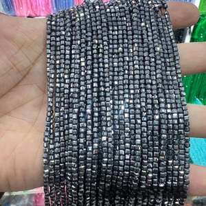 Close-up of faceted black Terahertz stone beads with metallic finish on a long strand