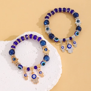 Macro-opname van Hamsa Hand en Evil Eye bedeltjes op blauwe kristallen kralenarmbanden