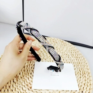 Detalle de una lujosa diadema negra con brillantes de colores sobre fondo trenzado