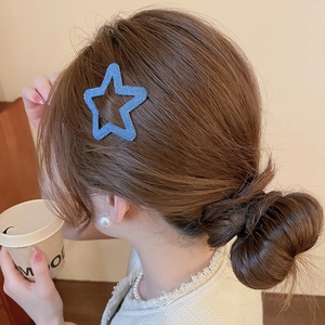 Close-up of a blue denim star hair clip styled as a side barrette on a woman's hair