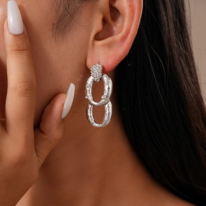 Dettaglio orecchini in zircone argento con design in metallo plissettato e texture