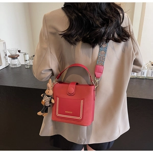 Red bucket bag featuring a colorful bohemian strap and a cute bunny pendant