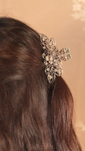 Close-up of vintage silver floral hair claw clip with rhinestones in long brown hair