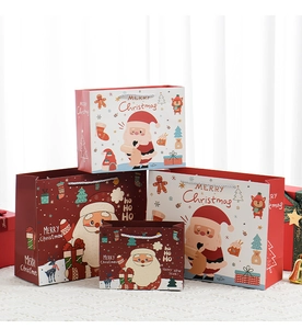 Close-up of assorted Christmas gift bags with reindeer and Santa motifs on a textured table
