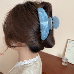 Pince à cheveux florale en acrylique marbré bleu portée sur un modèle féminin
