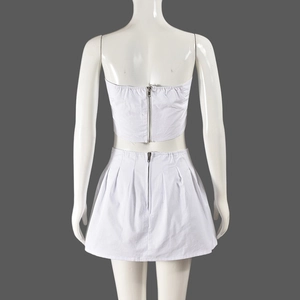 Back view of white two-piece set featuring a tube top, pleated mini skirt, and metal zippers