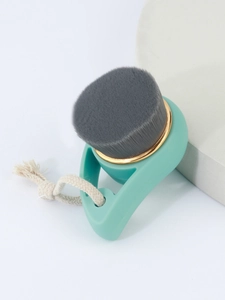 Close-up of mint green facial brush with bamboo charcoal bristles and a gold metal ring