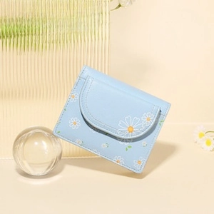Close-up of a light blue card holder with daisy print and curved flap design