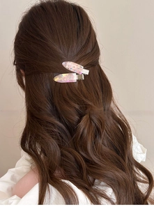 Detail showing two sparkling water-drop hair clips with rhinestones on wavy hair