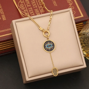 Gold-tone Hamsa hand and blue evil eye necklace set displayed on a premium jewelry box