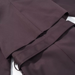 Détail du trench-coat prune foncé montrant le tissu tissé et la ceinture assortie