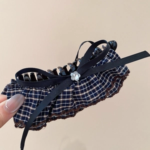 Close-up of a blue plaid hair claw clip with a black bow and crystal flower detail