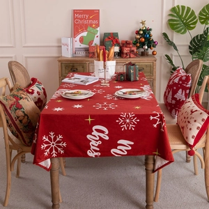 Red Christmas tablecloth with white snowflake prints and Merry Christmas text on a wooden table