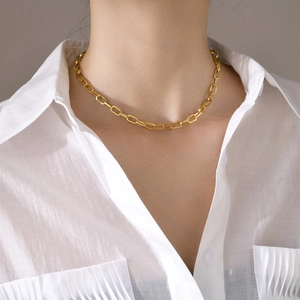 Dettaglio della collana a catena a graffetta placcata oro 18k su una camicia bianca