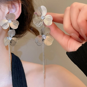 Detail of silver drop earrings featuring brushed metal flower petals and long chain tassels