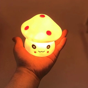 Warm glowing mushroom night light with cartoon face held in hand at night
