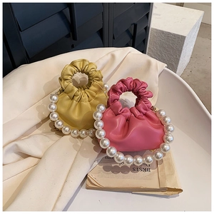 Detail of yellow and pink ruched handbags featuring large decorative pearl handles