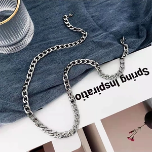 Silver stainless steel NK Cuban link necklace displayed on white card and denim fabric
