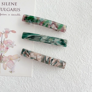 Detailed macro view of three marble pattern acetate hair clips with spring metal closure