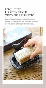 Détail d'une main posant du savon dans un porte-savon vintage en fonte avec oiseau
