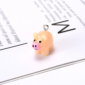 Macro shot of a pink resin pig charm with black eyes and a metal ring for DIY jewelry