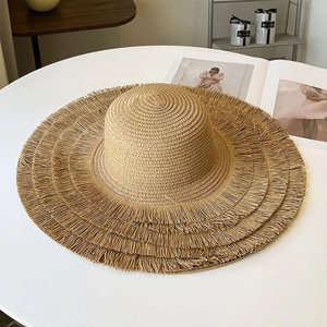 Macro shot of khaki woven straw hat with detailed tiered fringe edge and wide brim design