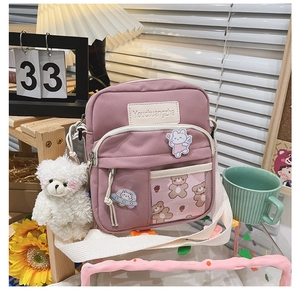 Détail du sac bandoulière en toile violette avec poche transparente et ours en peluche