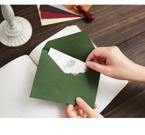 Detailed view of forest green linen texture envelope with vintage greeting card and wax seal