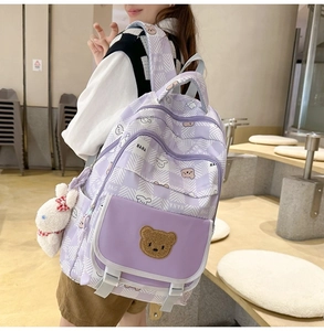 Detail of purple plaid schoolbag with plush bear patch and bunny pendant