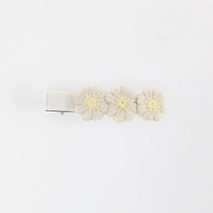Close-up of three cream embroidered knit flowers on a fabric-covered hair clip