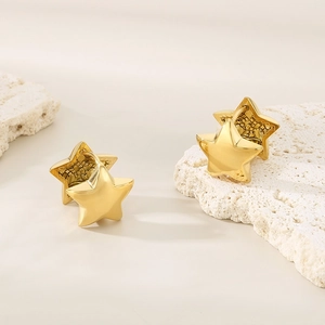 Chic 3D star-shaped gold earrings placed on a white stone background with soft lighting
