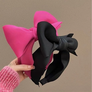 Detailed close-up of oversized satin bow headbands in vibrant rose pink and classic black