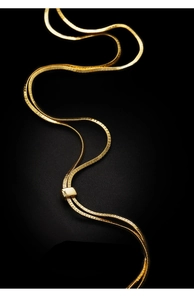 Detail of elegant gold snake chain necklace arranged in S-curves on black background