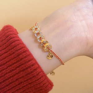 Détail du bracelet pièces d'or avec corde rouge tressée et zircons étincelants