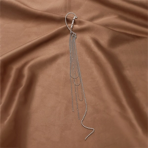 Silver tassel ear cuff with pearls and rhinestones on elegant silk fabric background