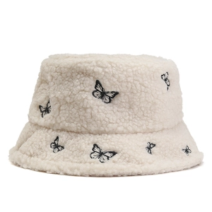 White faux shearling bucket hat with black butterfly embroidery for winter warmth