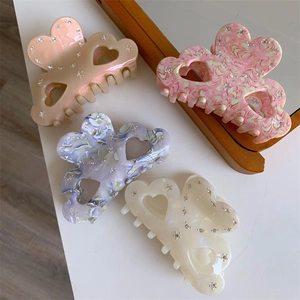 Flat lay of four marble-patterned acetate hair claws with rhinestones on a table