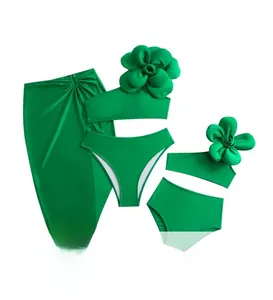 Detailed flat lay of a four-piece green swimsuit set with 3D floral accent and wrap skirt