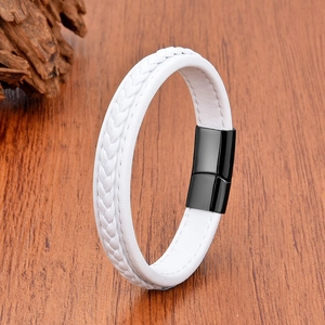 Close-up of white braided leather bracelet featuring a black magnetic metal clasp on wood