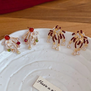 Detailed shot of gold plated fireworks earrings with red zircon and floral tassels