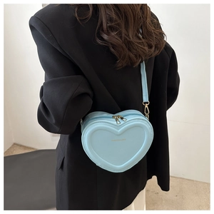 Close-up of light blue heart-shaped bag with gold hardware worn over a black blazer