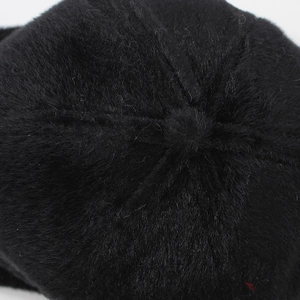 Detail shot of the top stitching and plush black faux fur texture on a warm winter cap