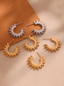 Detailed view of C-shaped sunburst earrings in polished gold and silver finishes