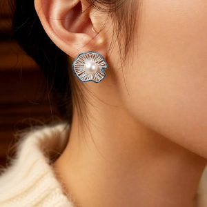 Detailed view of model wearing blue hollow flower earrings with a white pearl center