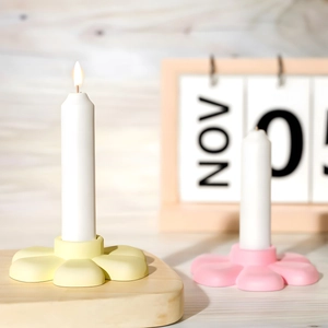 Détail d'un bougeoir fleur mat avec une longue bougie blanche sur fond de bois