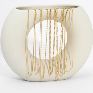 Detailed display of assorted gold-plated titanium steel chains on white ceramic decor