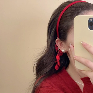 Close-up of red flower petal tassel earrings and pearl stud on model in profile