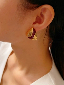 Close-up of vintage 18K gold and burgundy enamel earrings worn by a female model