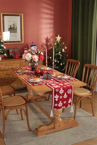 Close-up of red Christmas table runner with white snowflake patterns and tassel detail